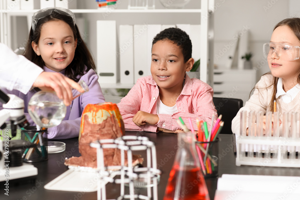 Little children having experiment with teacher and chemical volcano in science classroom