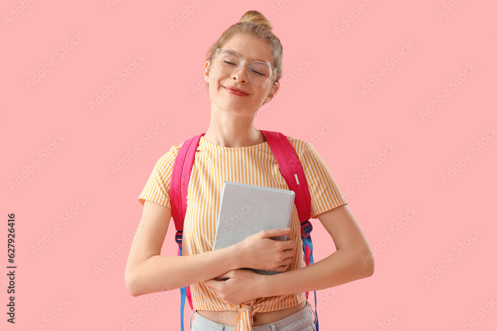 Happy female student with book on pink background