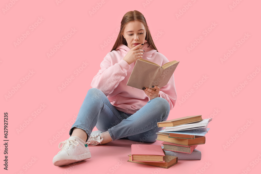 Teenage girl reading book on pink background