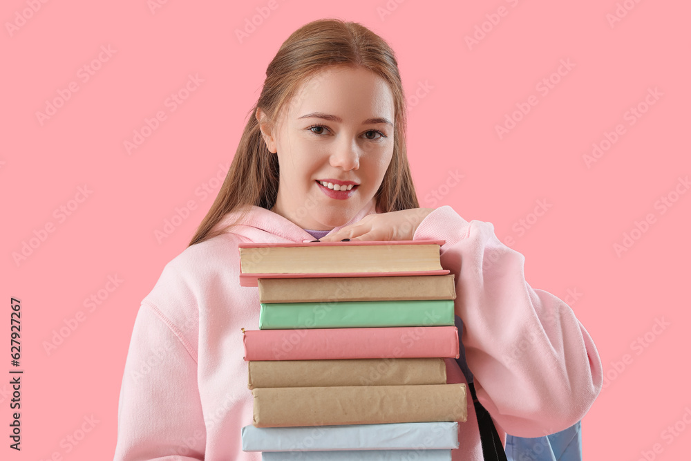 Female student with stack of books on pink background, closeup