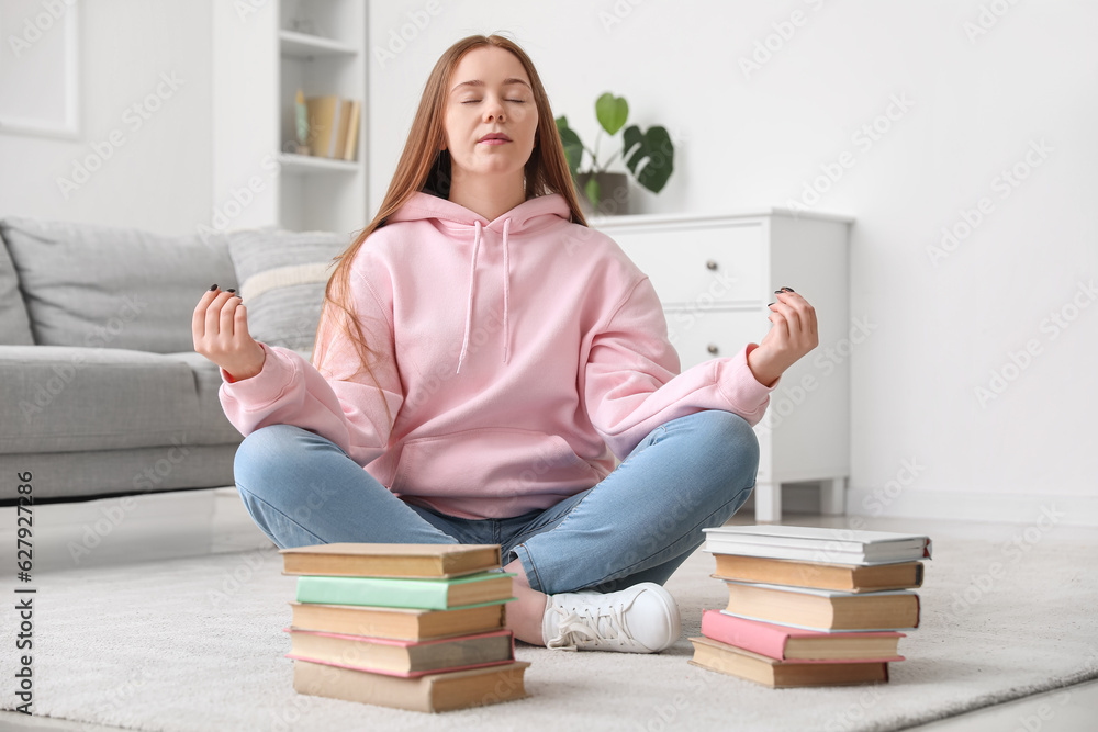 Teenage girl with books meditating at home