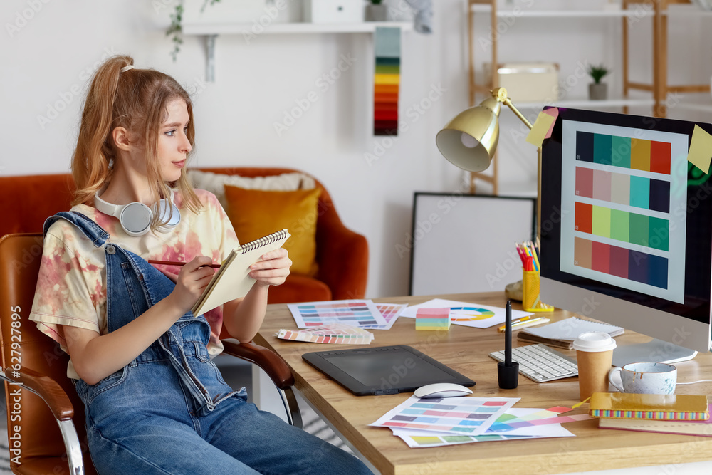 Female graphic designer working with notebook at table in office