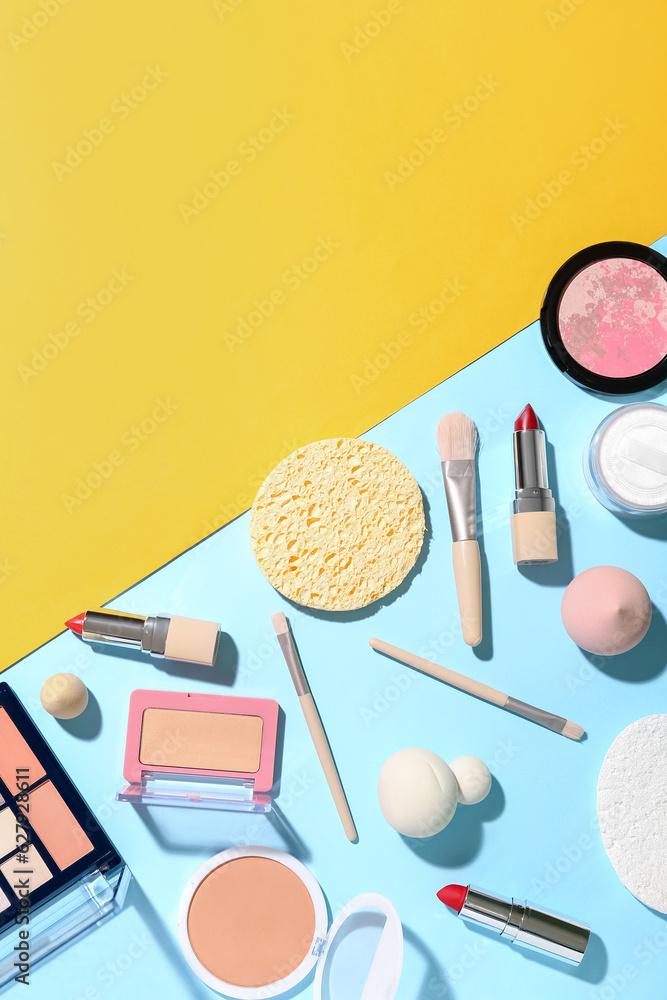 Decorative cosmetics with makeup brushes and sponges on color background