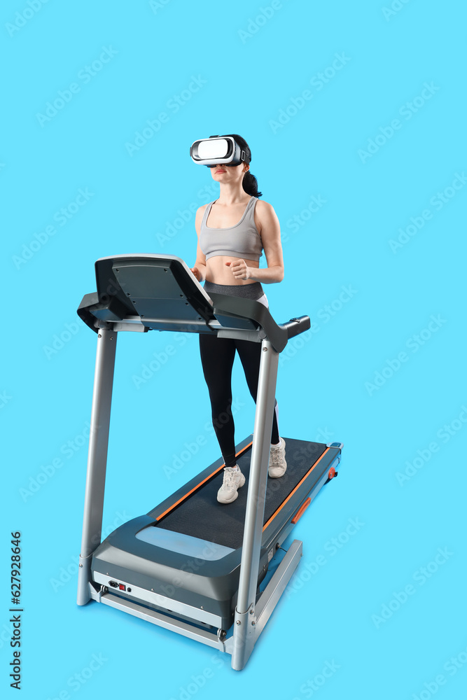 Beautiful woman in VR glasses training on treadmill against blue background