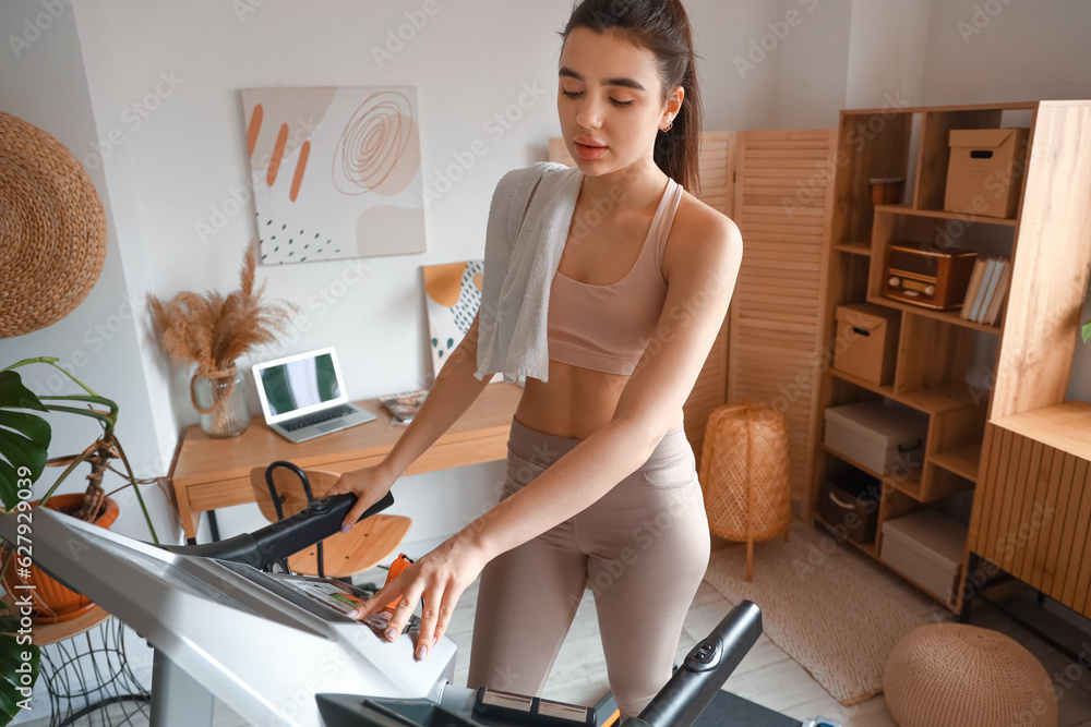 Sporty young woman training on treadmill at home