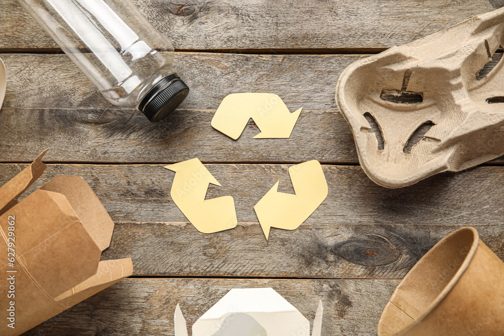 Recycling sign with garbage on wooden background