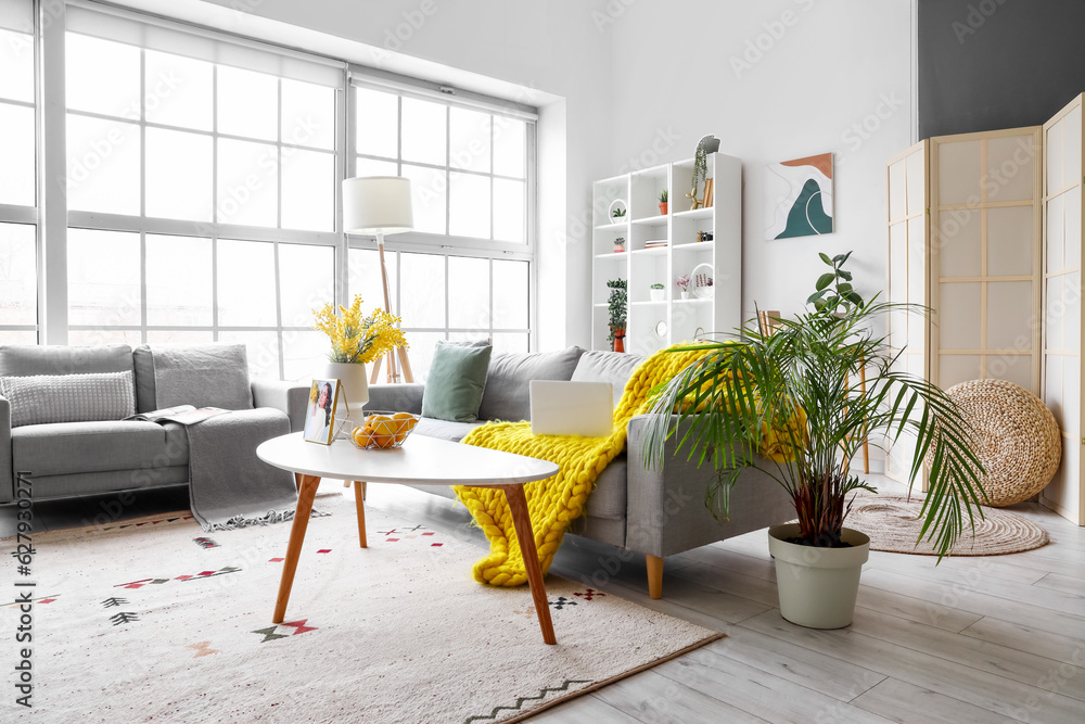 Interior of bright living room with cozy sofas near big window