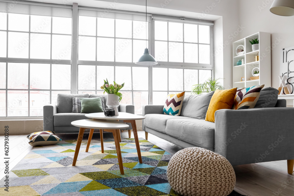 Interior of bright living room with cozy sofas and coffee table near big window