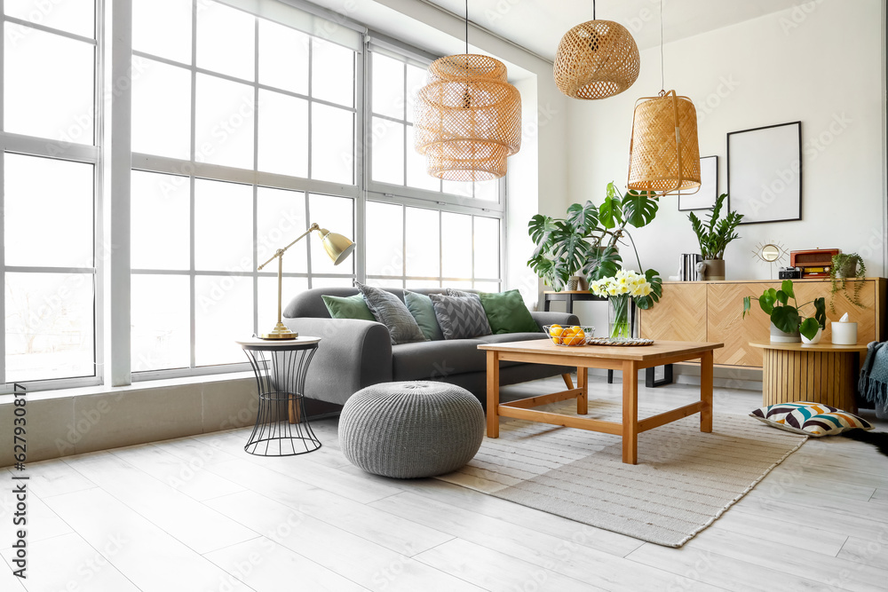 Interior of stylish living room with cozy sofa and table near big window