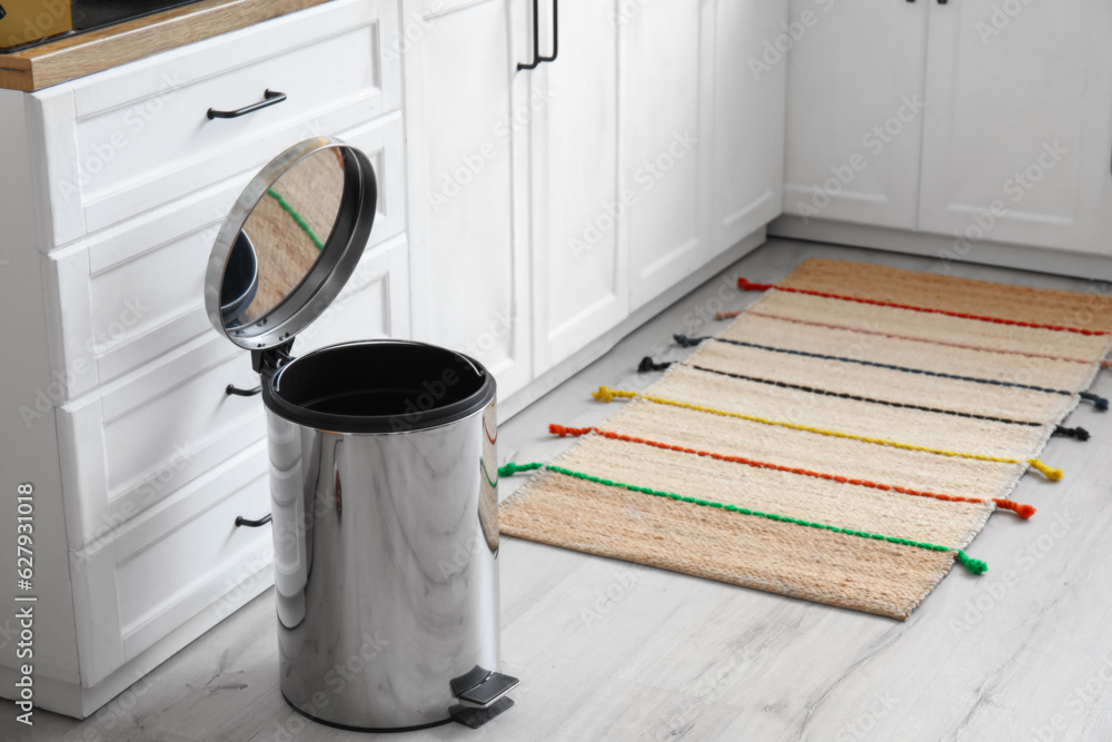 Opened metallic trash bin on floor in modern kitchen