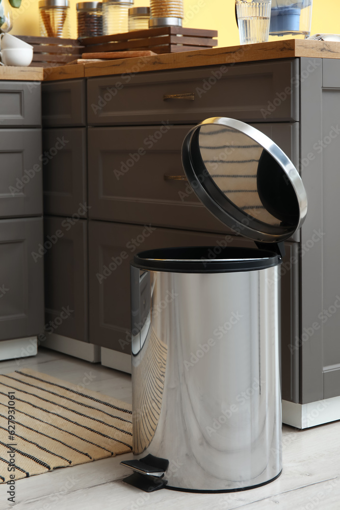 Opened metallic trash bin on floor in modern kitchen