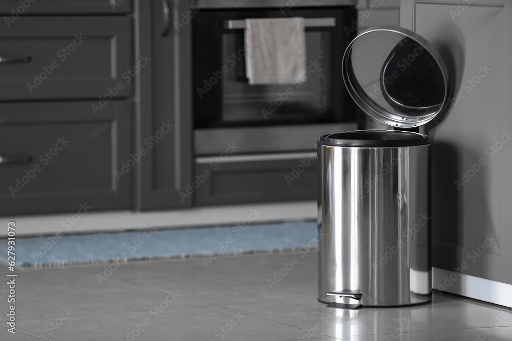 Opened metallic trash bin on floor in modern kitchen