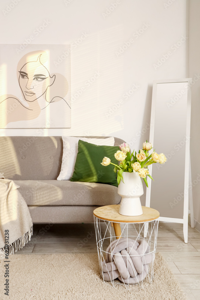 Interior of living room with grey sofa, table and mirror