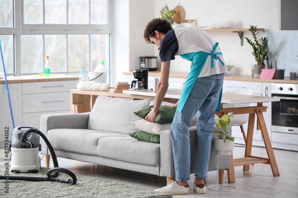 Young man fixing cushion at home