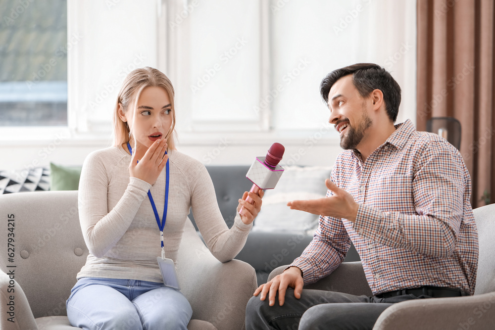 Female journalist with microphone having an interview with man in studio