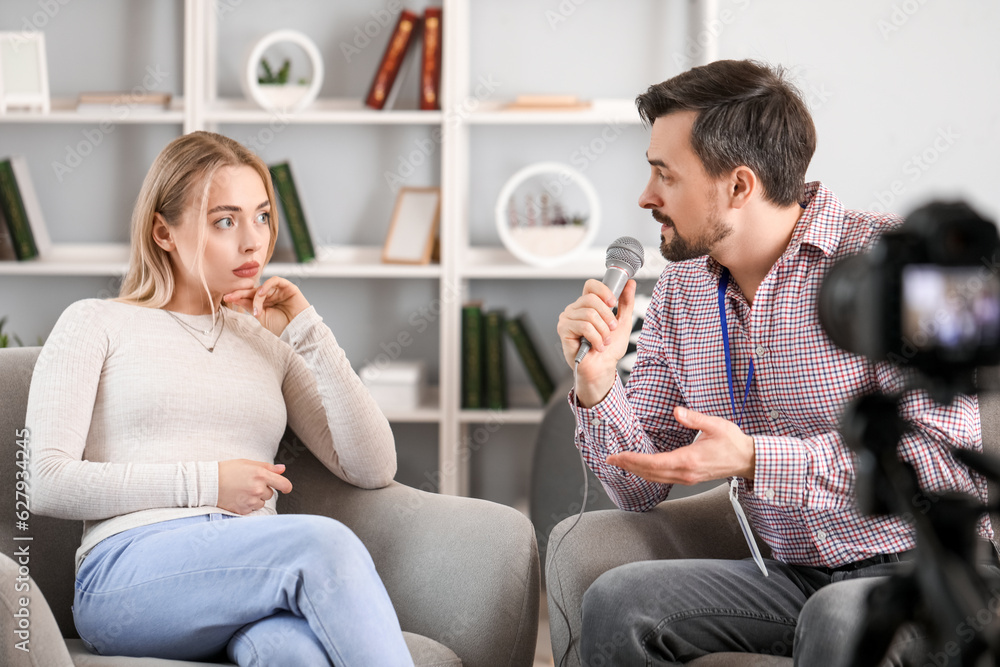 Male journalist with microphone having an interview with woman in studio