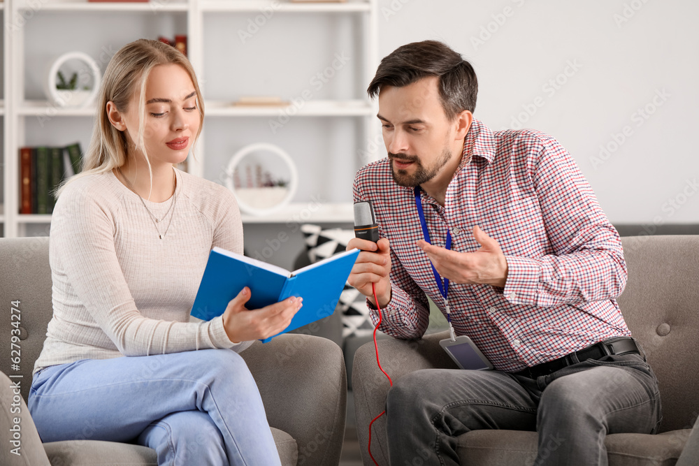 Male journalist with microphone having an interview with woman in studio