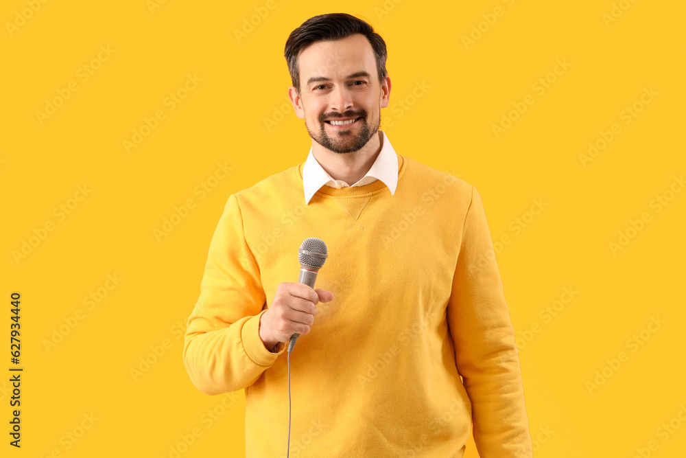 Male journalist with microphone on yellow background