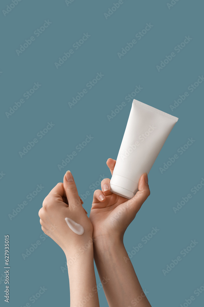 Hands of woman applying cream against blue background