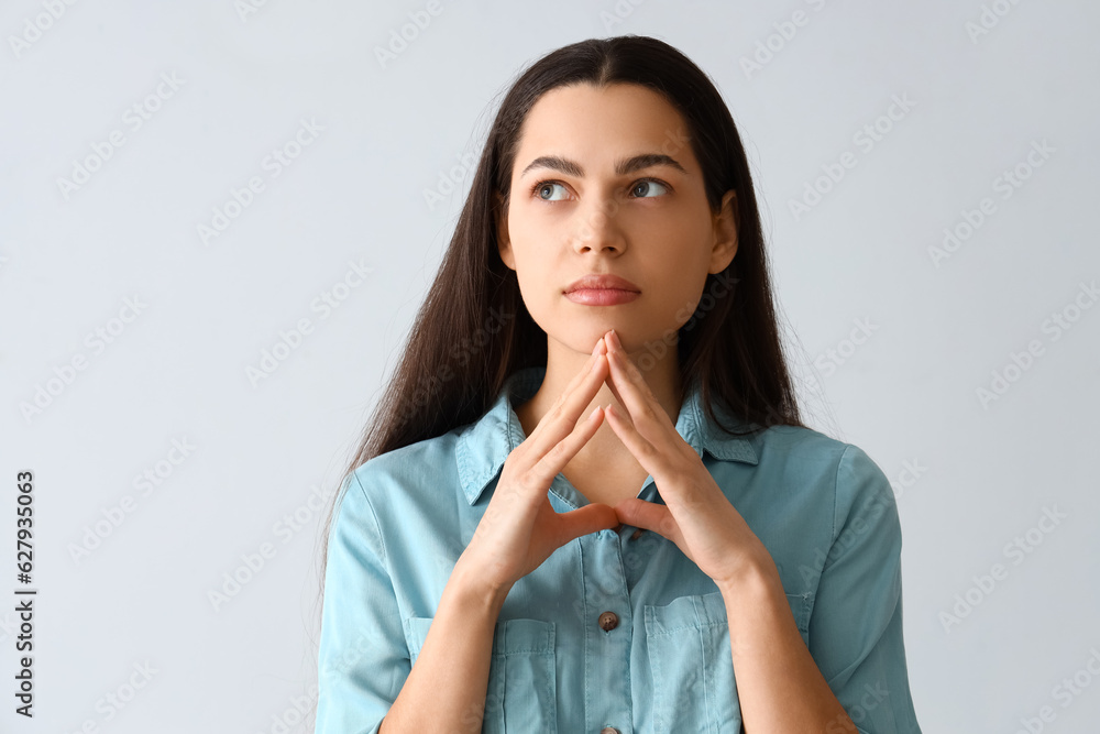 Thoughtful young woman on light background, closeup