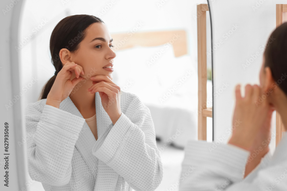 Young woman doing face building exercise near mirror in bathroom