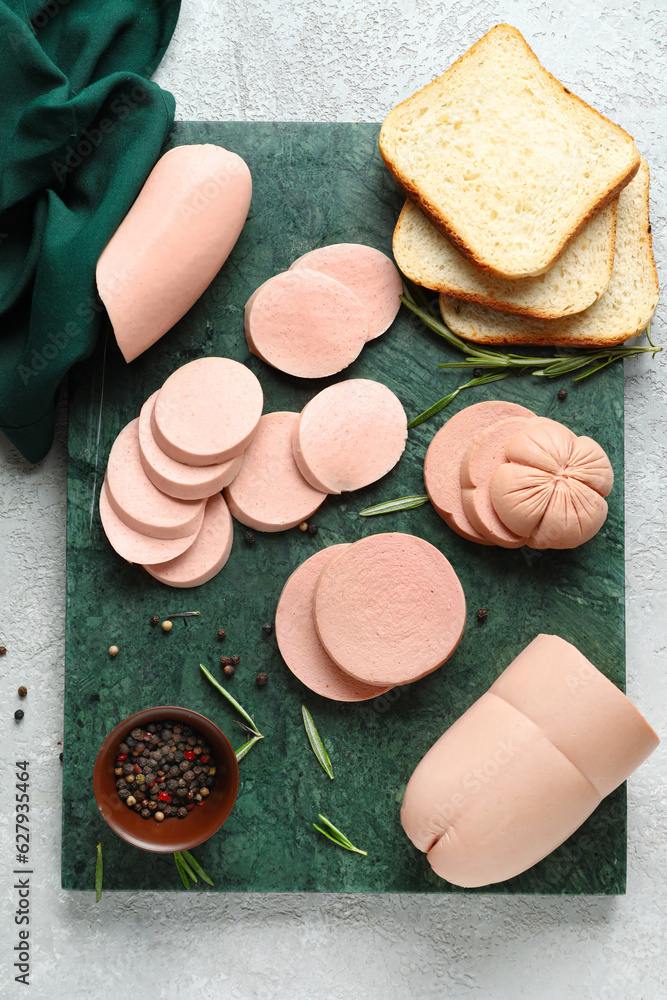 Slate board with tasty boiled sausages and bread on light background