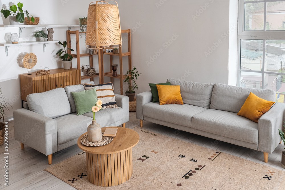 Interior of light living room with grey sofas and gerbera flowers on coffee table