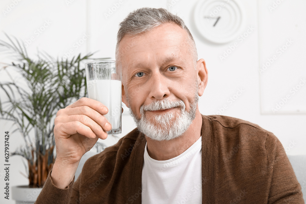 Mature man with glass of milk at home, closeup