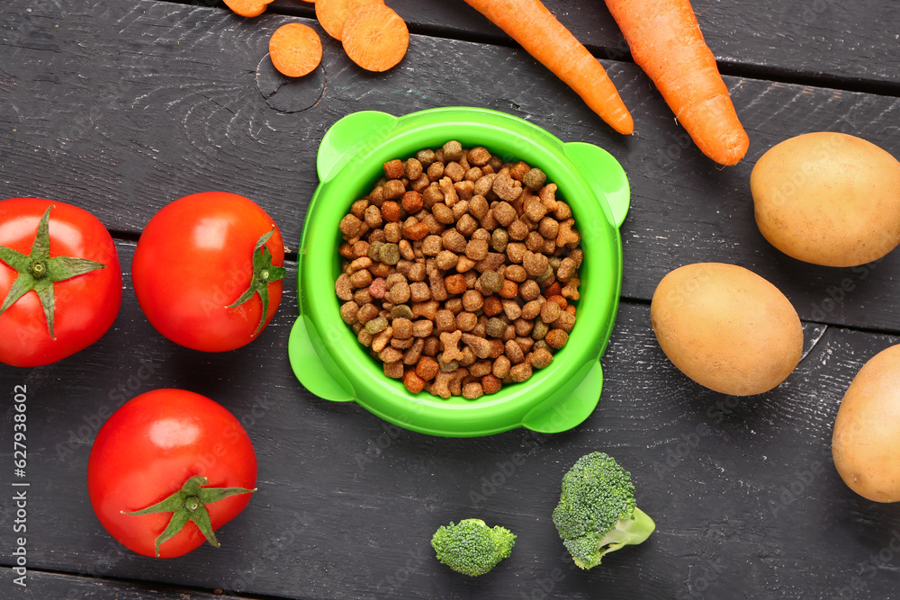 Bowl with dry pet food and natural products on dark wooden background