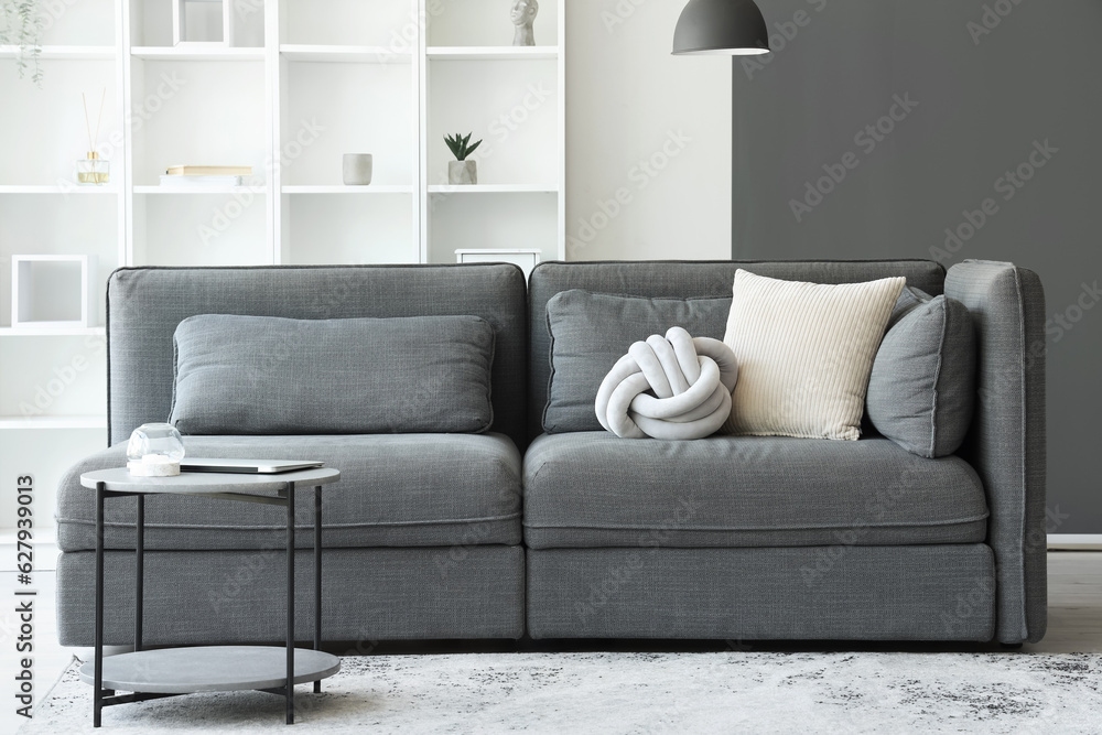 Interior of light living room with cozy grey sofa and coffee table