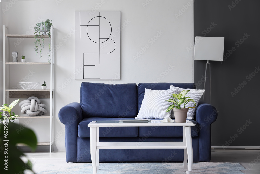 Interior of stylish living room with cozy blue sofa and modern laptop on table