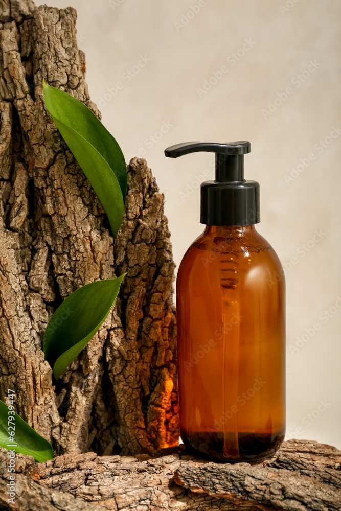 Composition with bottle of cosmetic product, tree bark and plant leaves on light background, closeup