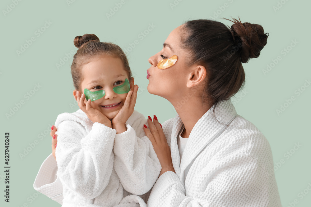 Little girl and her mother with under-eye patches on green background