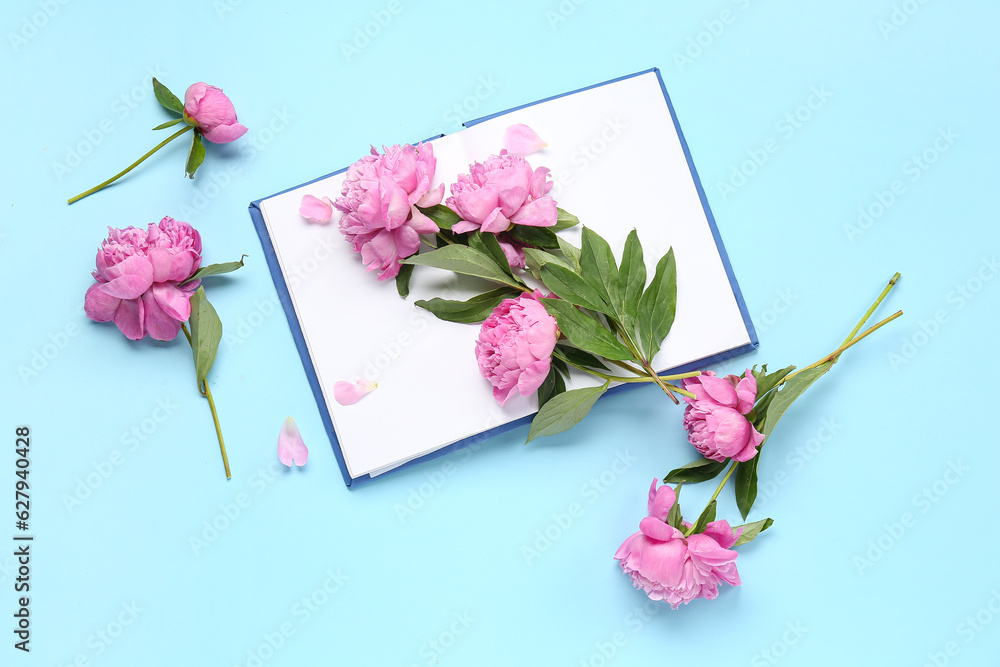 Composition with blank open book and beautiful peony flowers on color background