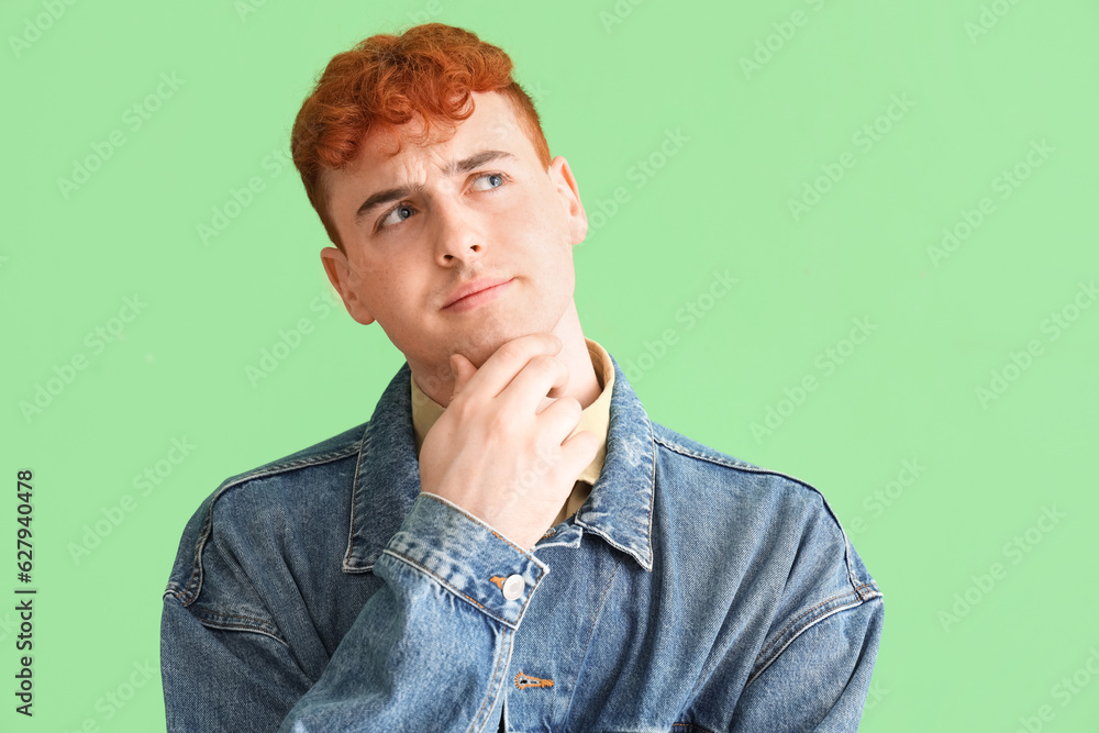 Thoughtful young redhead man on green background, closeup