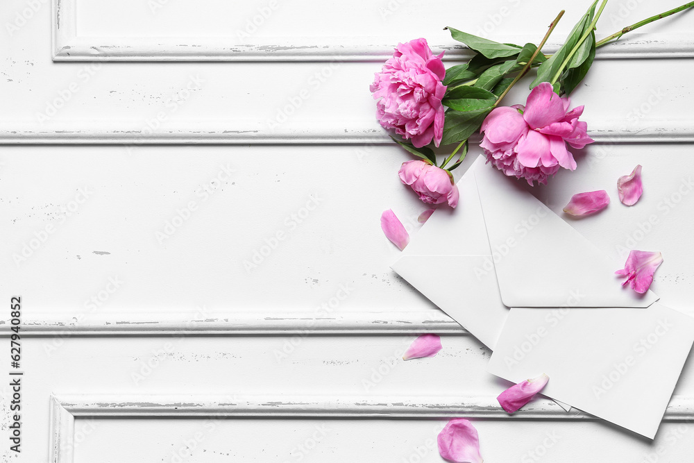 Composition with blank card, envelope and beautiful peony flowers on light background