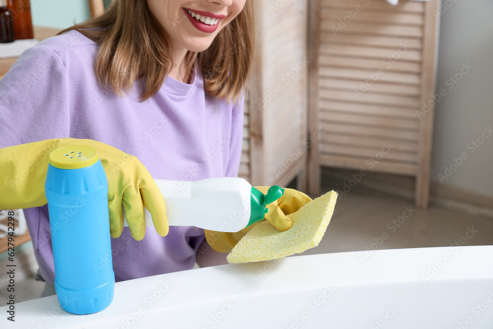 Young woman cleaning bathtub in bathroom, closeup