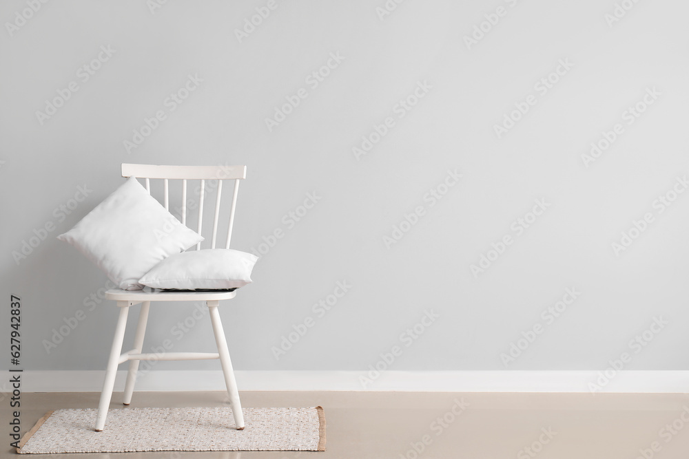 Chair with pillows on rug near white wall