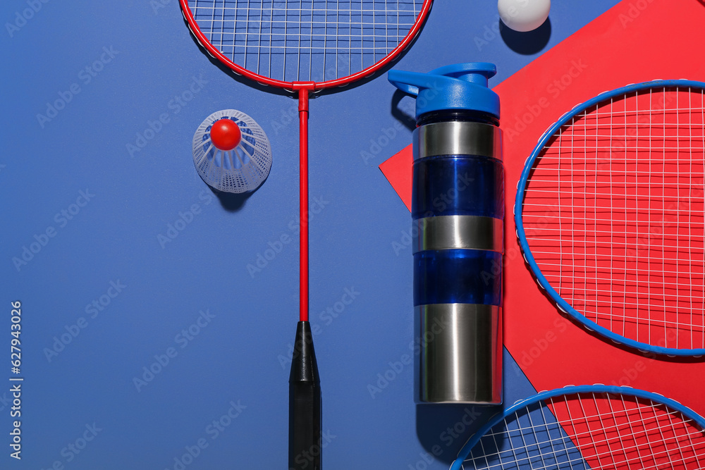 Composition with bottle of water, rackets, ball and shuttlecock on color background