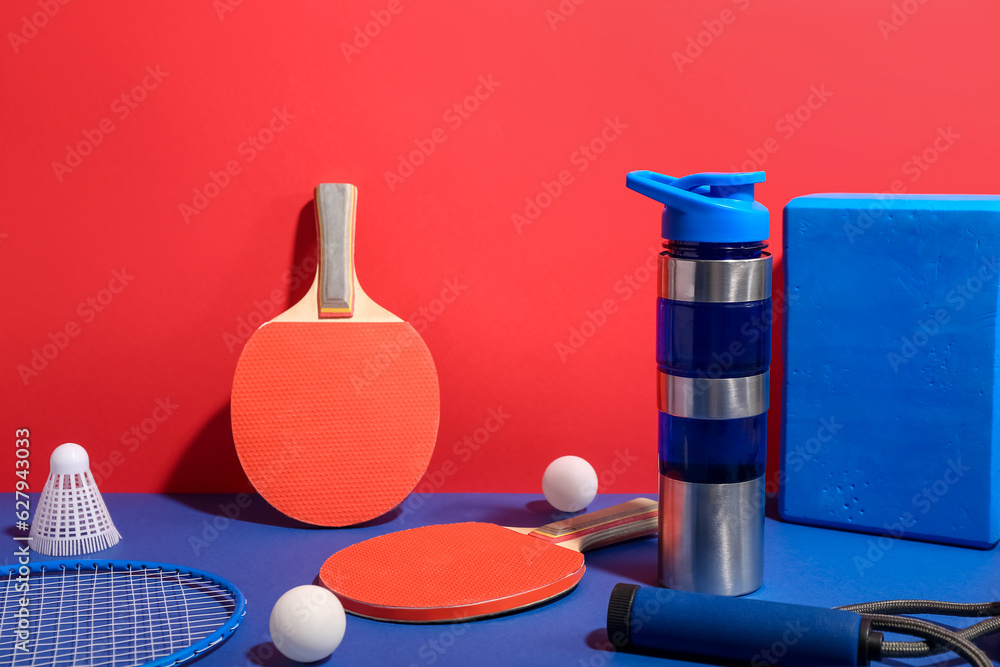 Bottle of water and different sports equipment on color background