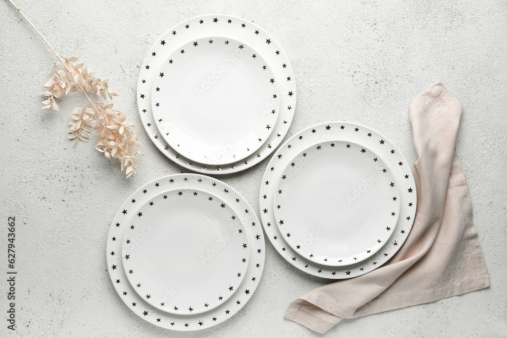 Set of clean plates and floral decor on white table