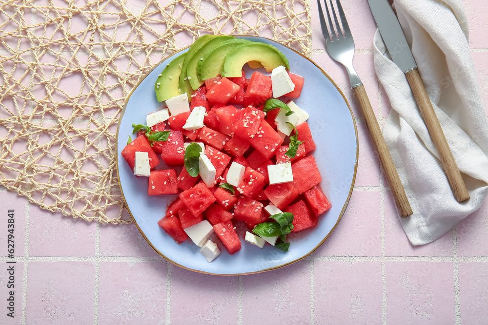 Plate of tasty watermelon salad on pink tile background