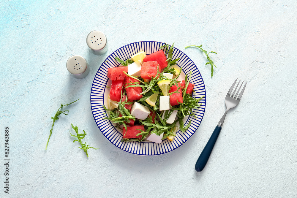 Plate of tasty watermelon salad on light blue background