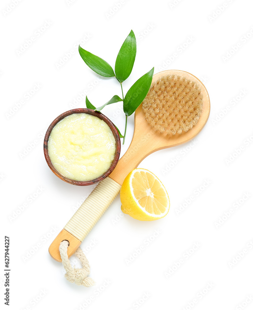 Bowl of lemon body scrub with massage brush isolated on white background