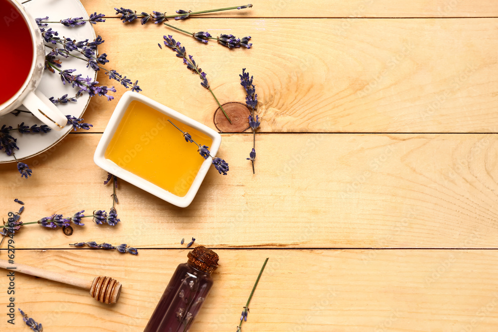 Bowl with sweet lavender honey and cup of tea on wooden background