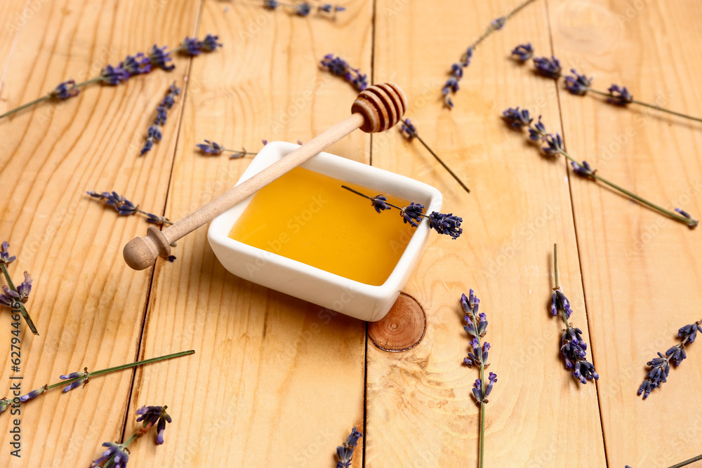 Bowl of sweet lavender honey, dipper and flowers on wooden background