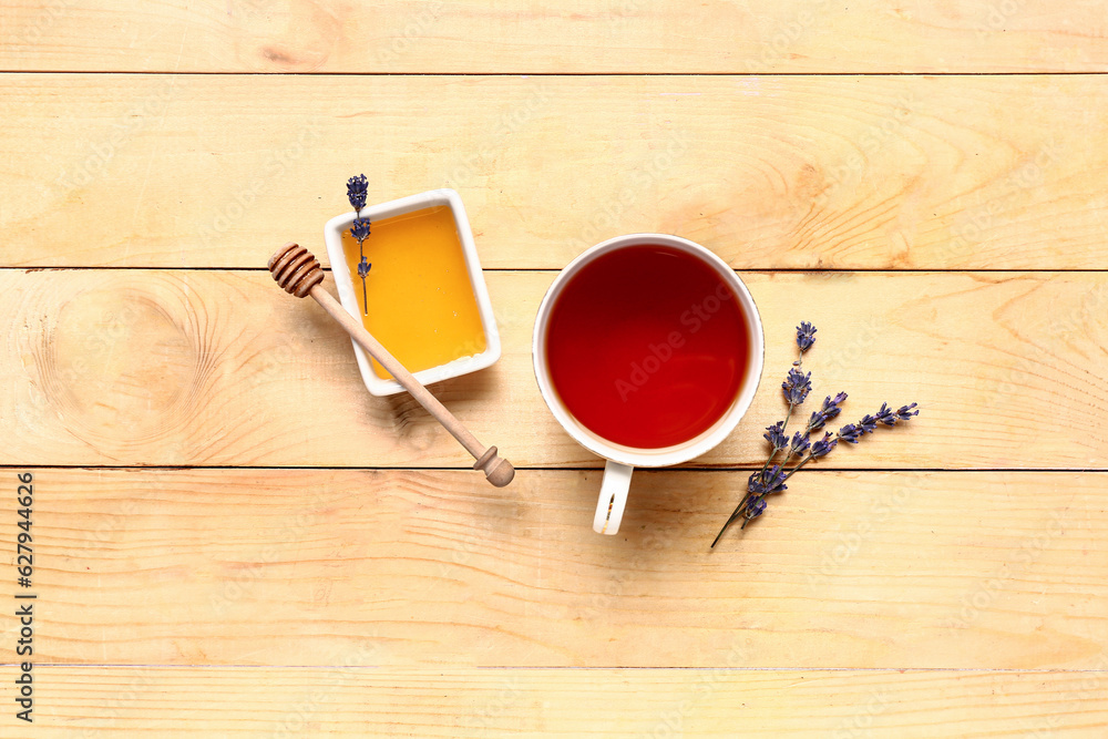 Bowl with sweet lavender honey and cup of tea on wooden background