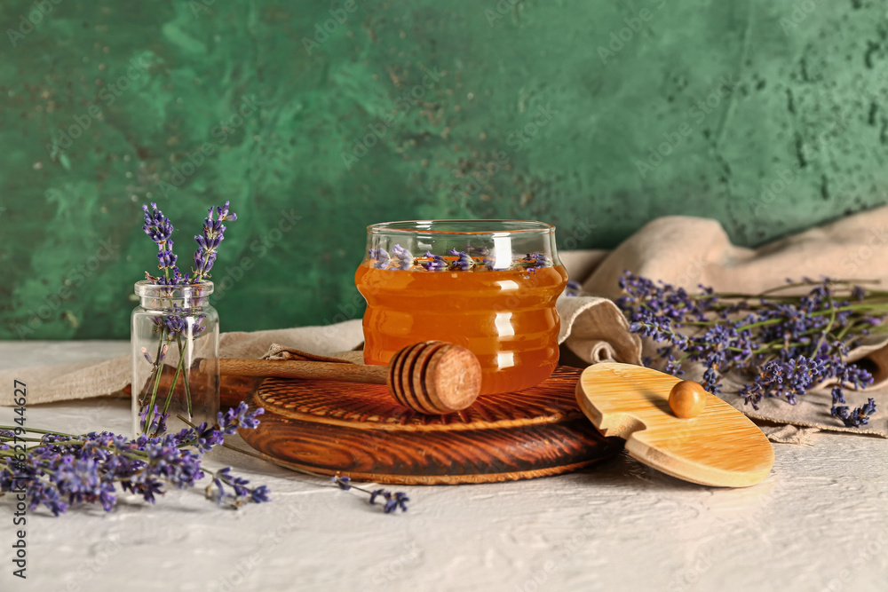 Wooden board with jar of sweet lavender honey, dipper and flowers on white table