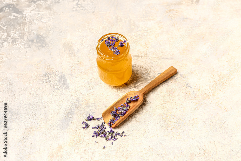 Jar of sweet lavender honey and flowers on white background