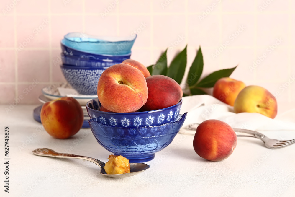 Bowl with sweet peaches on white table